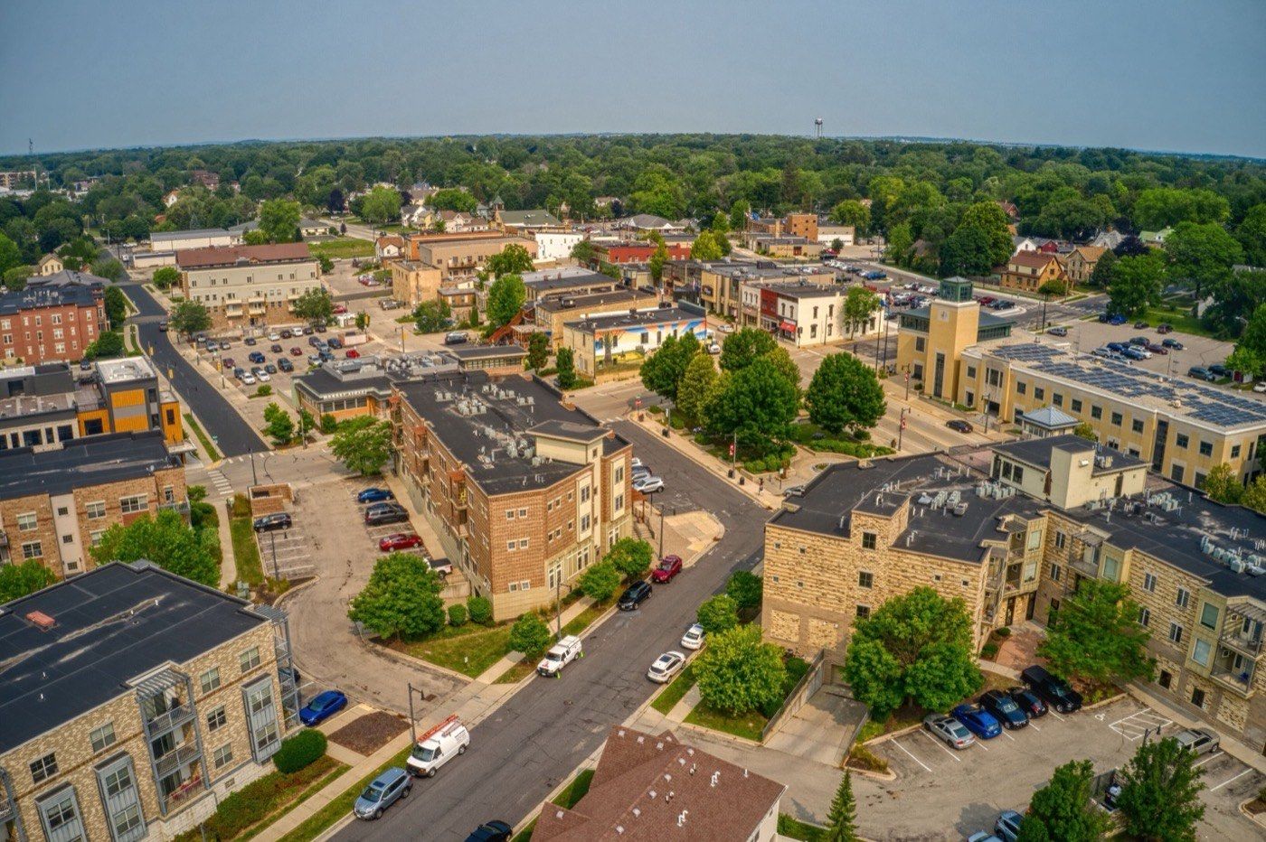 An aerial view of downtown Sun Prairie: new mixed-use brick apartment blocks around the old Main Street storefronts, with the water tower on the horizon.