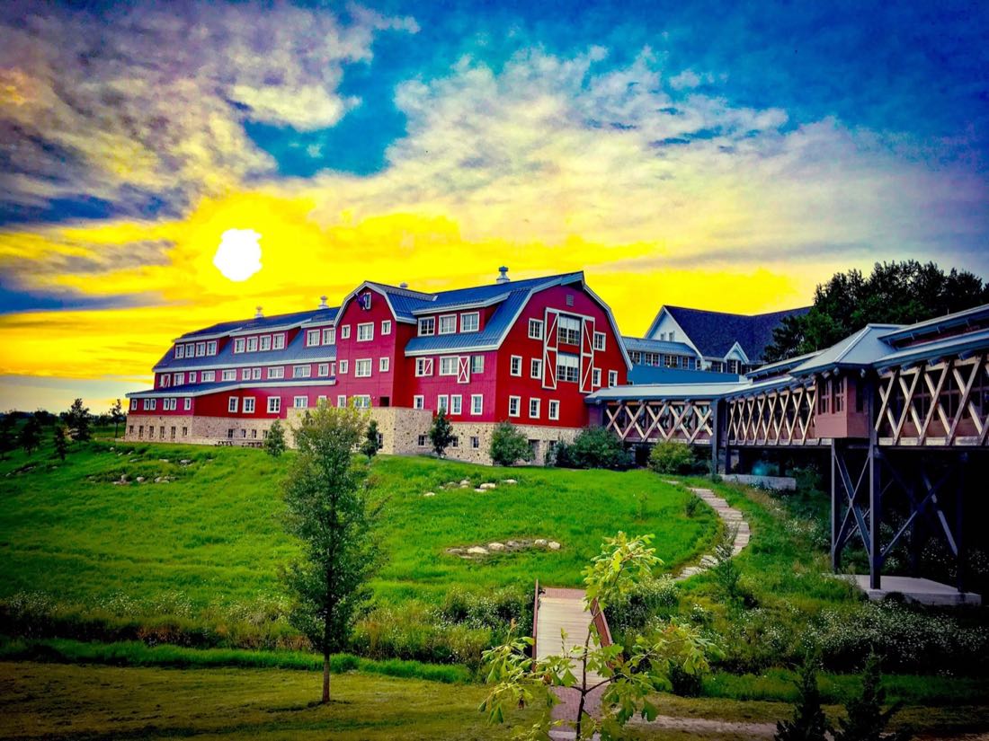 Epic Systems' campus in Verona: a large red barn-styled office building on a green hillside at sunset.